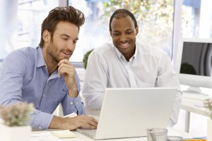 17132605 - young businessmen working together, using laptop computer, smiling.