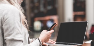 woman using her smartphone while working remotely on laptop picjumbo com e1488914320552