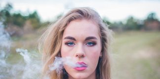 Woman vaping outside on grassy field