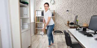 Happy Young Woman Cleaning the Floor with Mop in Modern Office