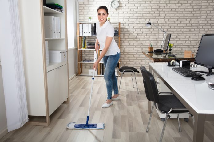 Happy Young Woman Cleaning the Floor with Mop in Modern Office
