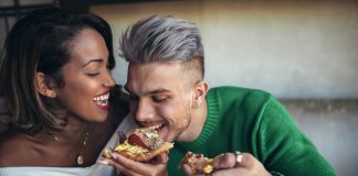 Couple eating pizza in modern cafe.