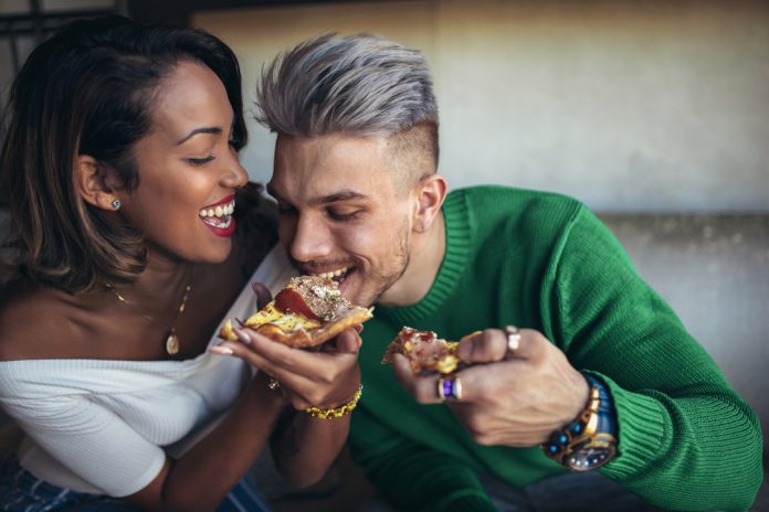 Couple eating pizza in modern cafe.