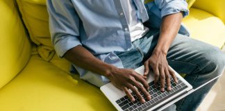 Man typing at laptop on yellow couch