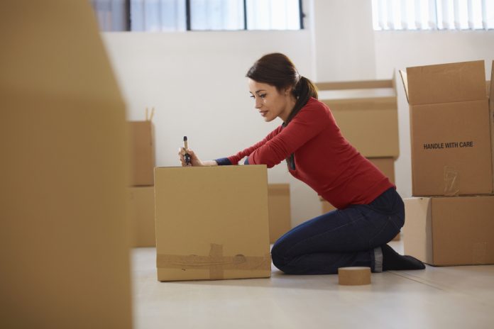 happy woman during move with boxes at new flat and packing carton