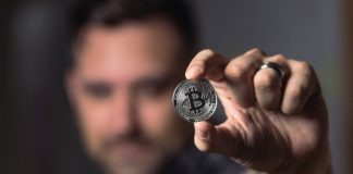 Man holding Bitcoin between fingers