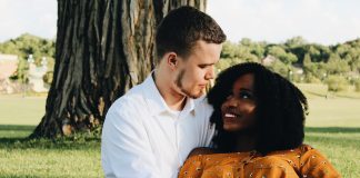 Couple sitting on grass with tree in background