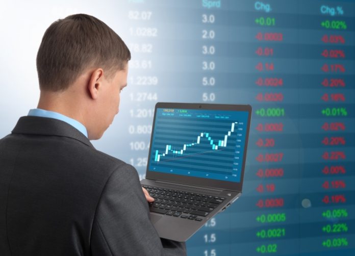 Businessman with Laptop on Stock Market Background