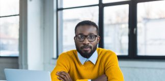 Businessman sitting with crossed arms and looking at camera in office