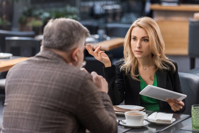 Businesswoman with tablet having business meeting with colleague in cafe