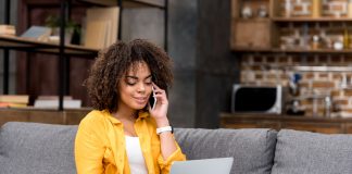 Woman typing on laptop and chatting on phone