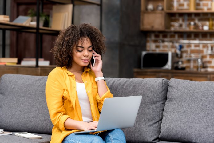 Woman typing on laptop and chatting on phone