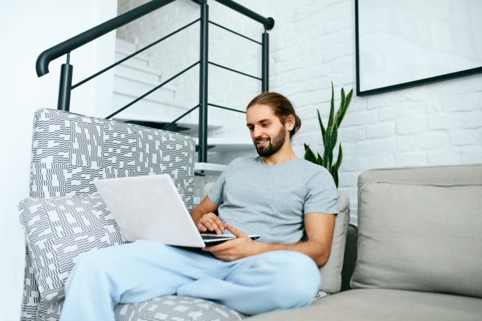 Young Man With Laptop At Home, Sitting on Sofa