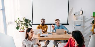 Smiling young business people talking during work in office