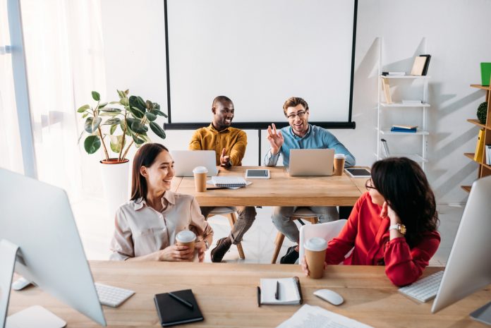 Smiling young business people talking during work in office