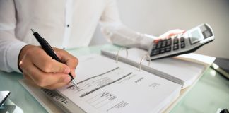 Close-up of a businessman's hand calculating bill in office