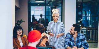 Positive female laughing together with group of young entrepreneurs