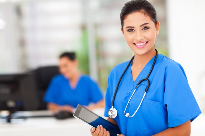 Attractive young female nurse holding tablet computer at workplace