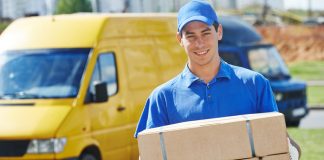 Smiling young male postal delivery courier man in front of cargo van delivering package