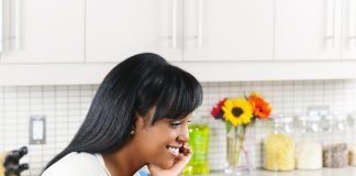 Smiling woman using computer in modern kitchen interior