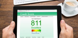 Close-up Of Person Hands With Digital Tablet Showing Credit Score At Desk