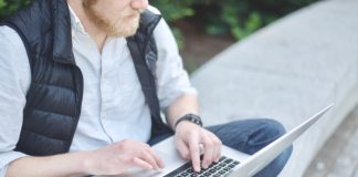 Man sitting on ground and typing on laptop