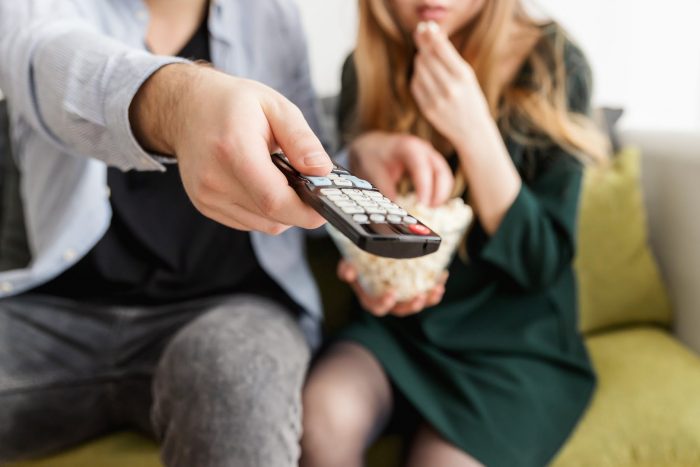 Woman and man watching TV with remote