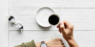 Person with coffee checking watch