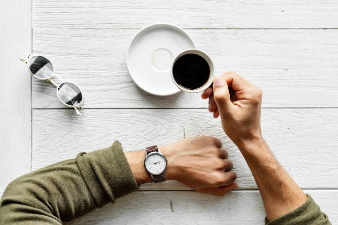 Person with coffee checking watch