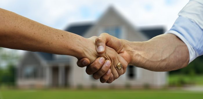 Handshake in front of real estate property