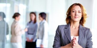 Image of business leader looking at camera with interacting partners at background