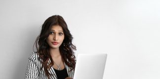 A beautiful young woman working on laptop against a white background