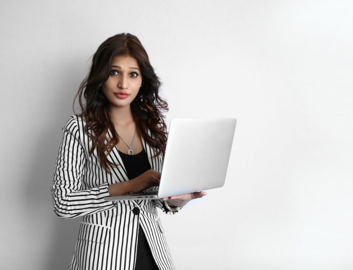 A beautiful young woman working on laptop against a white background