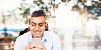 Young office worker using his phone in a cafe