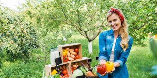 Attractive farmer showing ripe bell peppers at farmer market