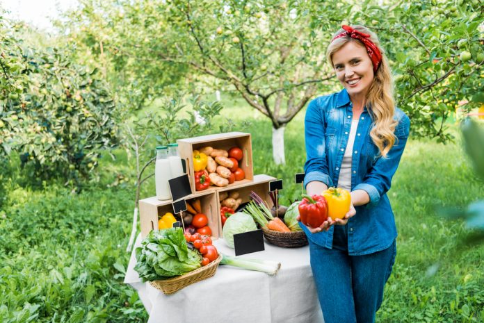 Attractive farmer showing ripe bell peppers at farmer market