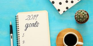 Top view 2019 goals list with notebook, cup of coffee over wooden desk