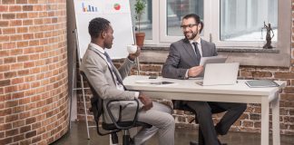 Business partners sitting at office table, drinking coffee and having discussion