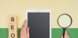 Top view of female seo manager holding digital tablet and magnifier