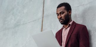 Serious casual businessman using laptop on grey background