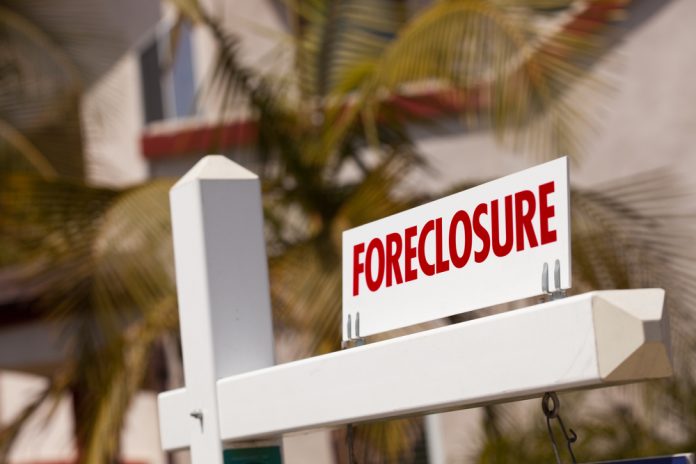 Close-up Foreclosure Real Estate Sign in Front of House.