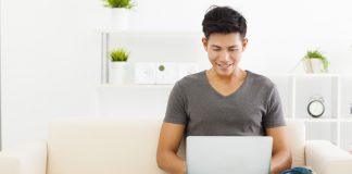 young man sitting on sofa and using laptop