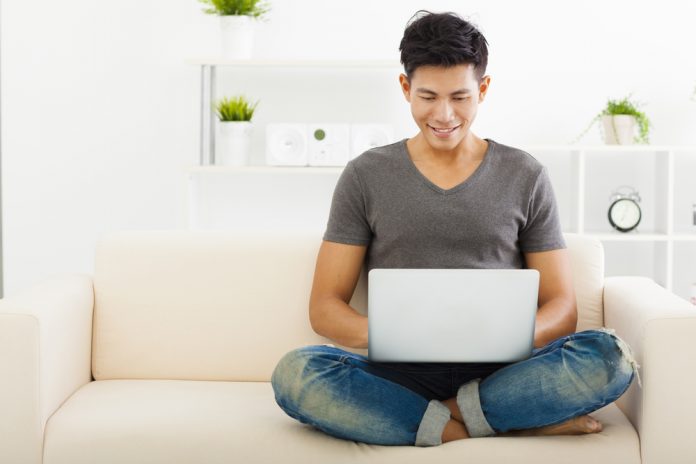 young man sitting on sofa and using laptop