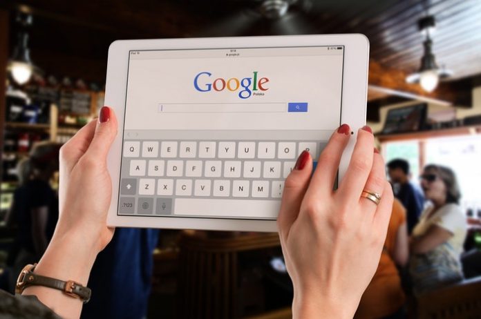 Woman holding tablet with Google homepage on screen
