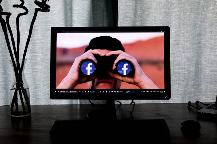 Facebook in binoculars on laptop