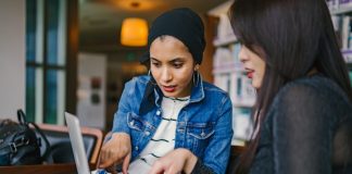 Two women pointing at laptop screen