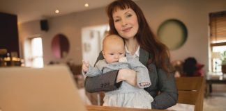 Woman holding baby and working at laptop