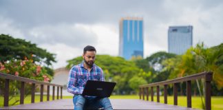 Young Man In Park Using Laptop Computer