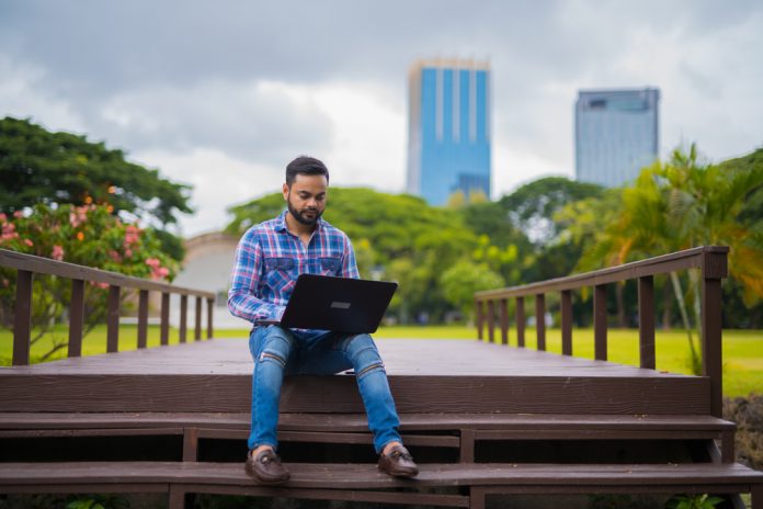 Young Man In Park Using Laptop Computer