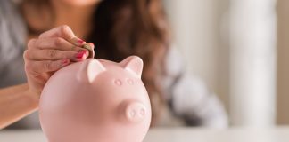 Woman Putting Coin In Piggy Bank